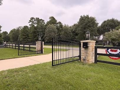 Arched black iron estate gate with stone columns and lanterns on acreage property in Willis TX