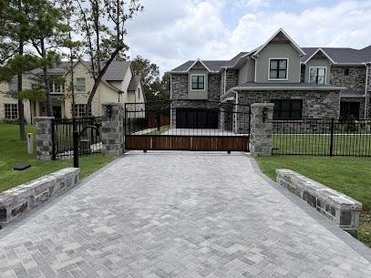Ornamental iron driveway gate with stone pillars on upscale residential property in The Woodlands TX